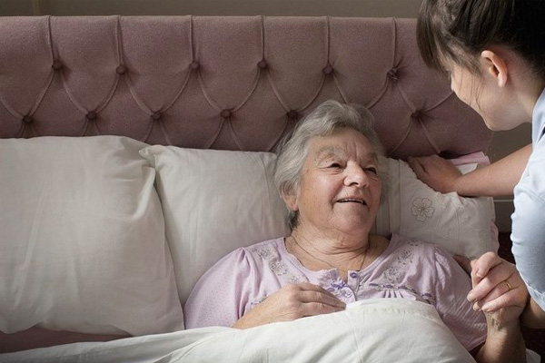 Elderly woman on a bed looked after a woman